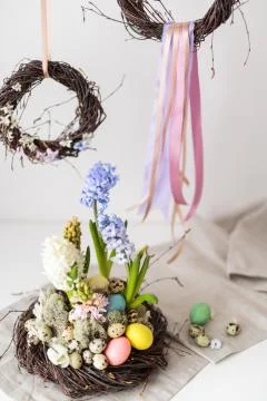 Flower arrangement in a nest with easter eggs on a white table Stock Photos