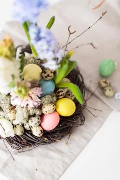 Flower arrangement in a nest with easter eggs on a white table Stock Photos