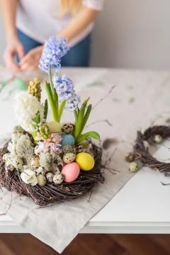 Flower arrangement in a nest with easter eggs on a white table Stock Photos