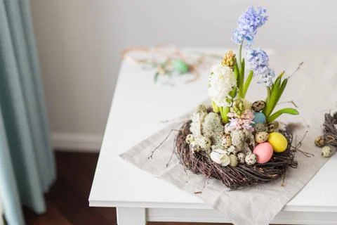 Flower arrangement in a nest with easter eggs on a white table Stock Photos