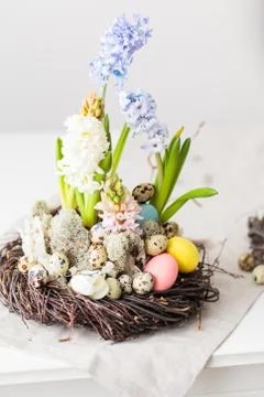 Flower arrangement in a nest with easter eggs on a white table Stock Photos