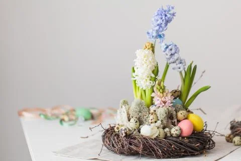 Flower arrangement in a nest with easter eggs on a white table Stock Photos