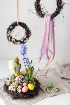 Flower arrangement in a nest with easter eggs on a white table Stock Photos