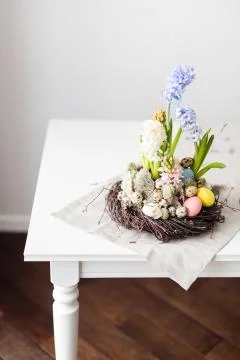 Flower arrangement in a nest with easter eggs on a white table Stock Photos