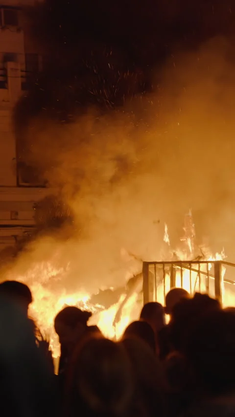 Flower figure on pole above burning falla during Las Fallas crema Stock Footage 336785327