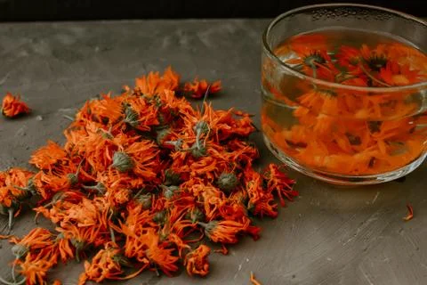 Flower light tea in a transparent large cup, orange calendula. Stock Photos