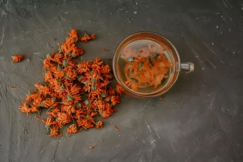 Flower light tea in a transparent large cup, orange calendula. Stock Photos