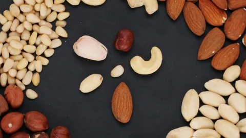 Flower made of nuts surrounded by a variety of nuts on the dark background Video stock 72850072