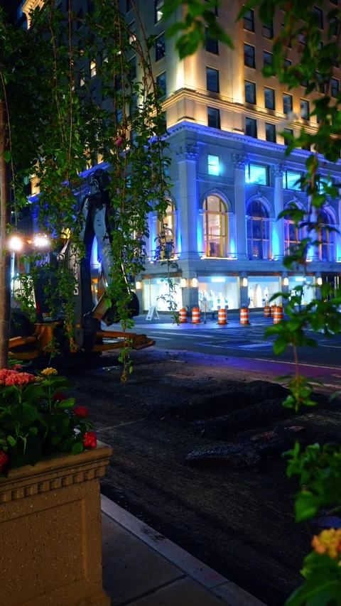 Flower planter and excavator in front of a blue lit building at night, Manhattan Stock Footage 336806951