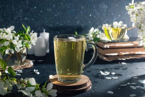Flower tea in a transparent mug on a dark background. Next to the cup are boo Stock Photos