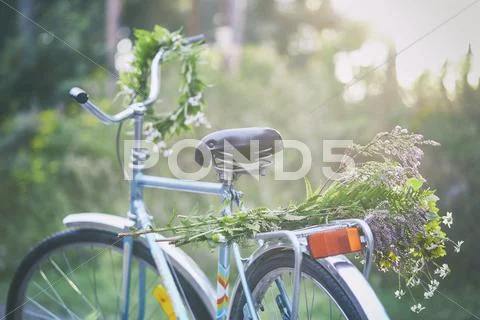 Flowers and garland on bicycle in garden Stock Photos
