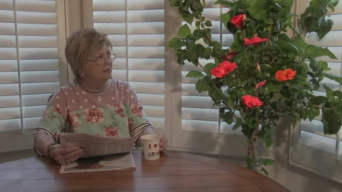 Flowers bloom as lady watches, while having morning coffee, 4K. Video stock 154111751