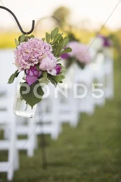 Flowers Hanging At End Of Rows Of Chairs At Wedding