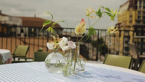 Flowers stand on a table in a vase in an open-air restaurant, the wind sways a Stock Footage 318066264