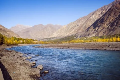 Flowing blue water of Gilgit River with mountains in the background, Pakistan. Stock Photos