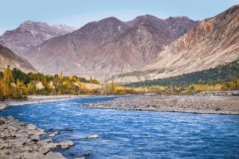 Flowing blue water of Gilgit River with mountains in the background, Pakistan. Stock Photos