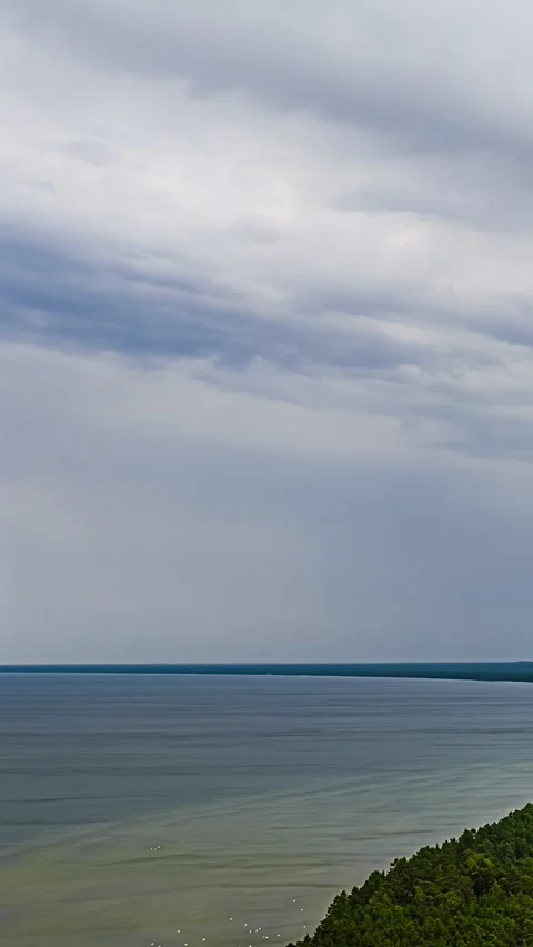 Flowing clouds moving above calm Baltic Sea coastline timelapse Stock Footage 340429583
