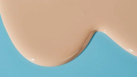 Flowing foundation tone on blue background. Brown cream texture close-up. Makeup Stock Footage 178608438