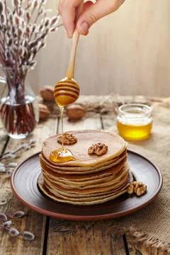 Flowing honey on stack of pancakes with nuts Stock Photos