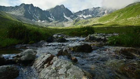 Flowing mountain stream in alpine valley with rocks Stockbeeldmateriaal 346681718