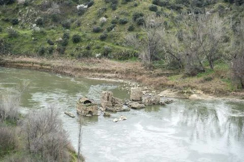 A flowing river filled with numerous rocks and trees in the backdrop Stock Photos