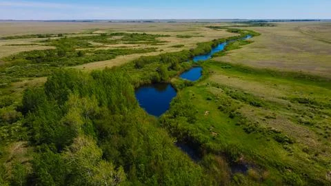 A flowing river in the midst of an endless field Stock Photos