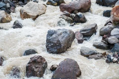 Flowing river water over large rocks and pebbles in a natural landscape Stock Photos
