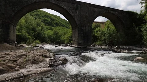 Flowing stream and ancient stone arched bridge from the 1700s Stock Footage 334027497
