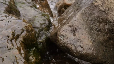 Flowing water among rocks creates serene nature. Clear water flows over stones Stock Footage 278975835
