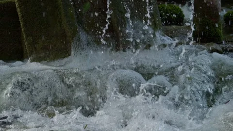 Flowing Water Cascading Over Rocks and Natural Structures in a Picturesque Stock Footage 307960684
