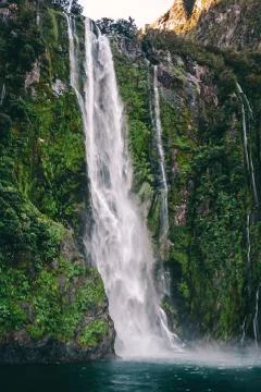 Flowing water fall into lake with green moss and leaves 스톡 사진