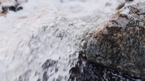 Flowing water gracefully navigates around rocks in a serene stream setting Stock Footage 294053955
