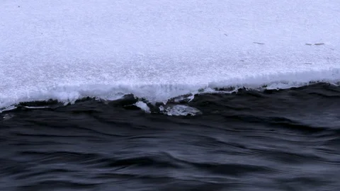 Flowing water from under the ice in winter. River flowing in winter. Stock Footage 99466022