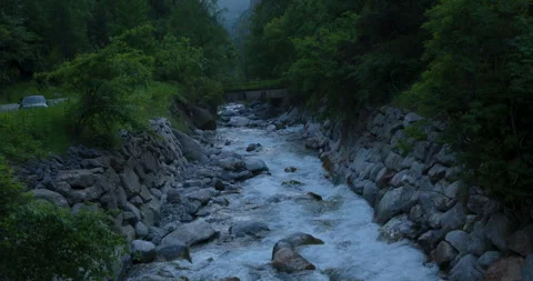Flowing waters illuminate a tranquil river at dusk near hidden mountain trails Stock Footage 314076573