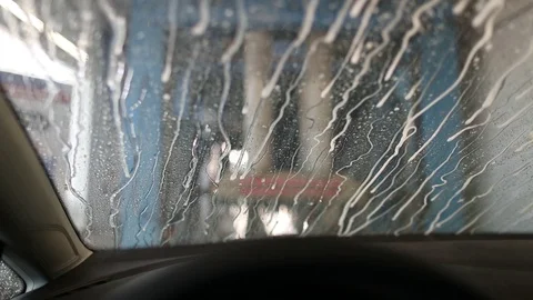 Flows of muddy water flow through the windshield of the car at the car wash Stock Footage 129709916