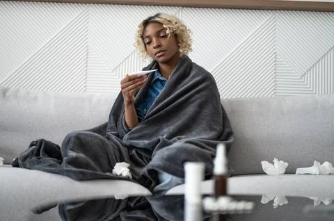 Flu and cold concept. Copyspace banner with black woman with fever on the couch. Stock Photos