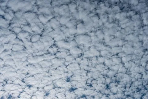 Fluffy altocumulus clouds fill the blue sky in this striking cloudscape. Stock Photos