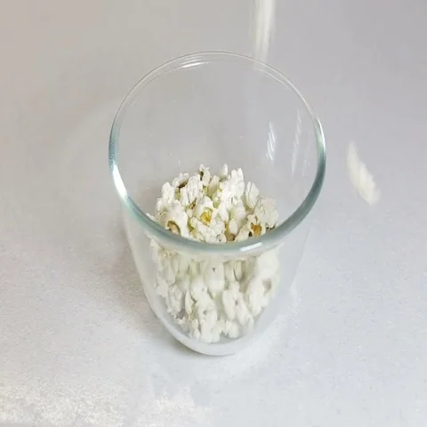 Fluffy bright pieces of popcorn falling in slow motion against a white backgroun Stock Footage 69510276