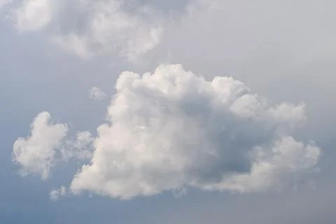 A fluffy cloud floats against a blue sky on a serene day, evoking relaxation and 写真素材
