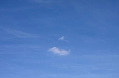 Fluffy cloud shapes drifting in the expansive blue sky during a serene afte.. Фото