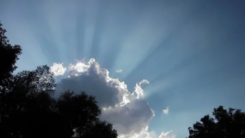 A fluffy cloud with sun rays floats across the blue sky Video stock 276552002