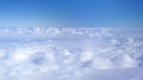Fluffy clouds in blue sky from aircraft window. View from window flying airplane Video stock 104961159