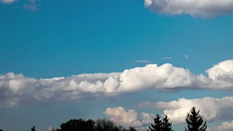 Fluffy clouds in blue sky move slowly over trees with birds rarely flying past Stock Footage 237605121