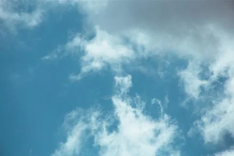 Fluffy clouds cover the summer blue sky Stock Photos