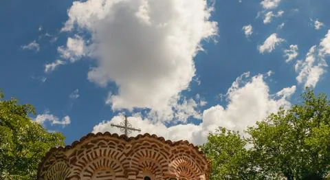 Fluffy clouds drift across a vibrant blue sky, as a prominent cross rests a.. Foto stock