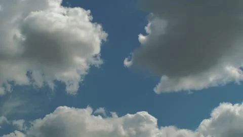 Fluffy clouds drift slowly across a bright blue sky 動画素材 337959971