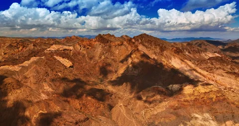 Fluffy clouds float in the sky above the rocks of Mojave desert Stock Footage 250761631