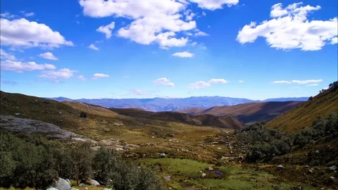 Fluffy clouds floating over green hill Stock Footage 77444867