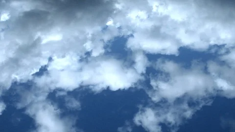 Fluffy clouds fly across a bright blue sky. Stock Footage 106354913