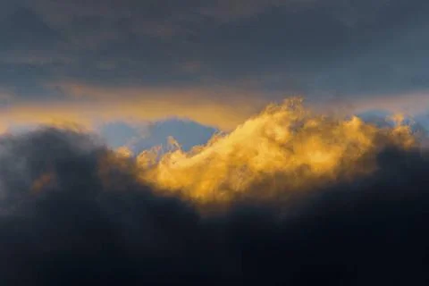  Fluffy clouds illuminated by disappearing rays at sunset and dark thunder... Stock Photos